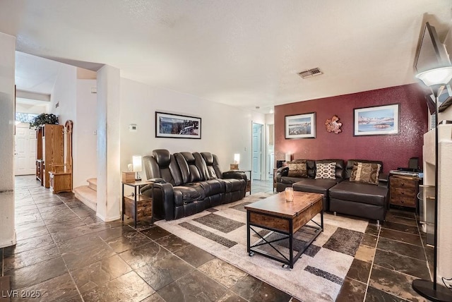 living room featuring visible vents, stone tile floors, and stairway