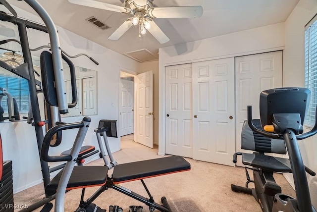 exercise area featuring visible vents, baseboards, light colored carpet, attic access, and ceiling fan