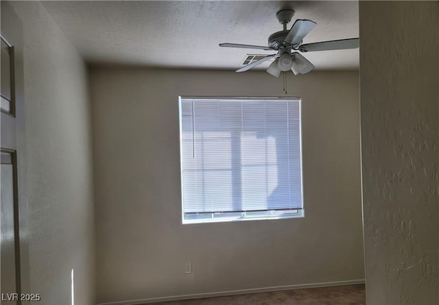 unfurnished room featuring a textured ceiling, a textured wall, a ceiling fan, and baseboards