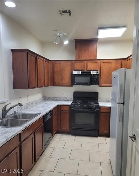 kitchen with light tile patterned floors, light countertops, visible vents, a sink, and black appliances