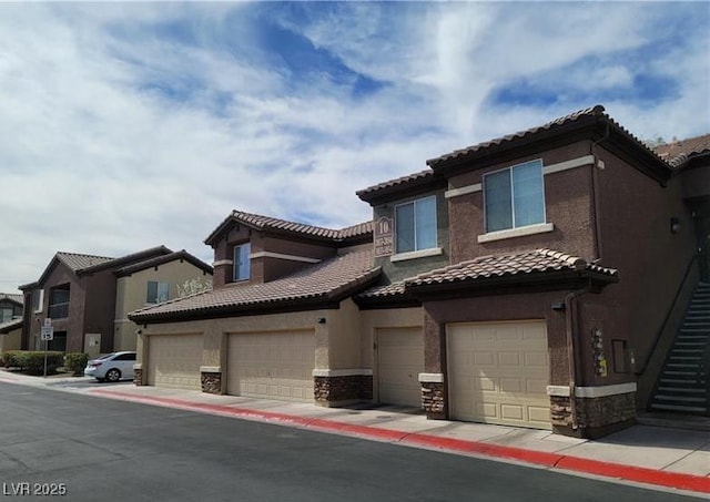 view of front of property with a garage, stone siding, a tile roof, and stucco siding