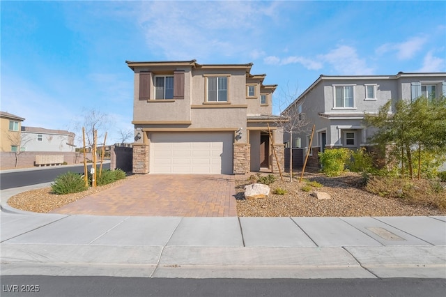 view of front of home featuring a garage, stone siding, fence, decorative driveway, and stucco siding