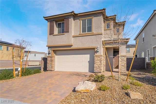 view of front of property with a garage, stone siding, fence, decorative driveway, and stucco siding