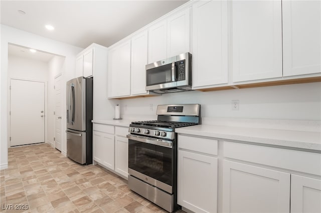 kitchen with stainless steel appliances, recessed lighting, light countertops, stone finish flooring, and white cabinets