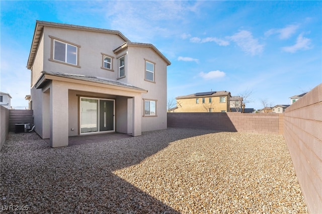 rear view of property featuring a fenced backyard, central AC unit, and stucco siding