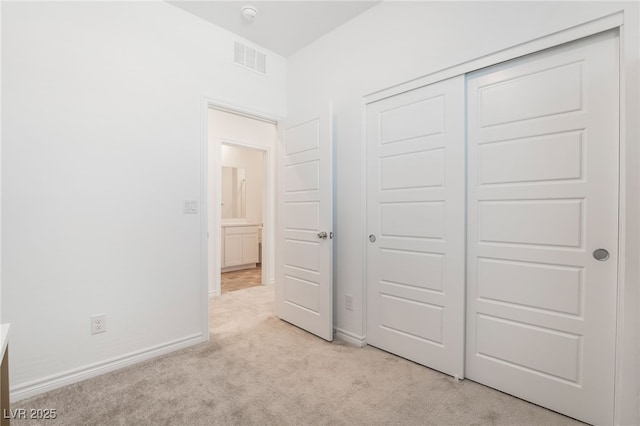 unfurnished bedroom featuring light carpet, a closet, visible vents, and baseboards