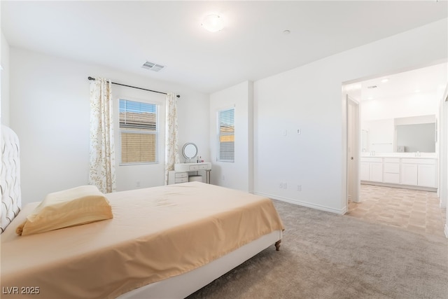 bedroom with light carpet, baseboards, visible vents, and connected bathroom