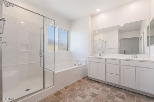 full bath with a sink, a shower stall, a bath, and double vanity