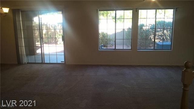 empty room with dark colored carpet and a healthy amount of sunlight