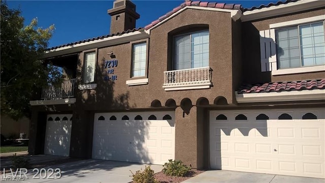 view of home's exterior featuring a garage, driveway, a chimney, a tiled roof, and stucco siding