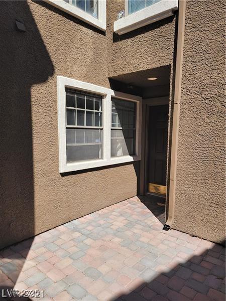 view of exterior entry with a patio area and stucco siding