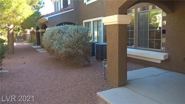 view of side of home with a patio, central AC, and stucco siding