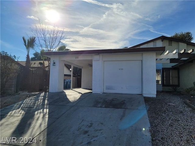 view of front facade with concrete driveway, an attached garage, a gate, and stucco siding