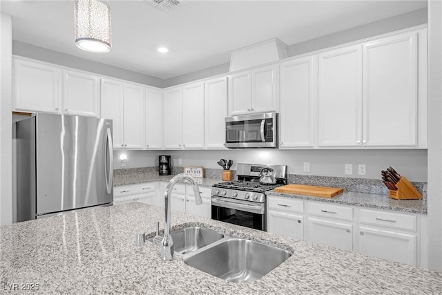 kitchen with recessed lighting, appliances with stainless steel finishes, white cabinetry, a sink, and light stone countertops