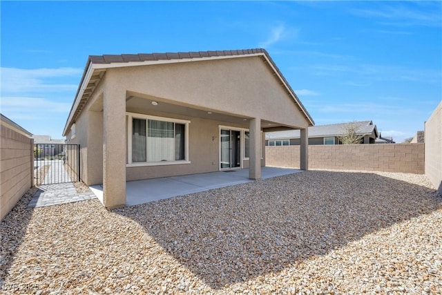 back of house with a patio area, a gate, fence, and stucco siding