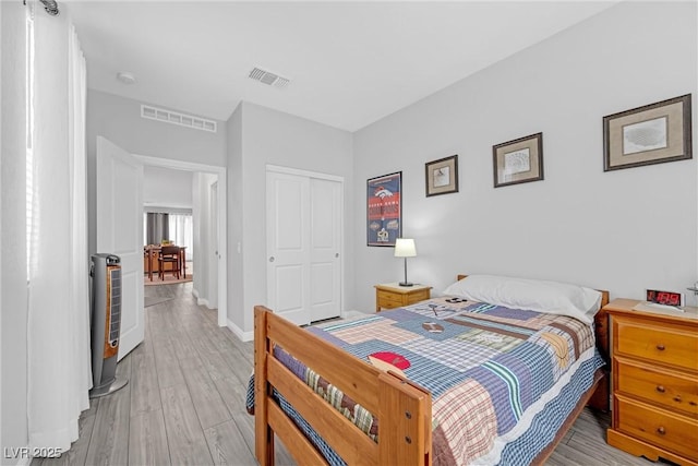 bedroom featuring light wood-type flooring, baseboards, visible vents, and a closet