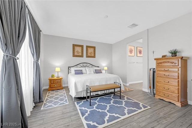 bedroom featuring wood finished floors, visible vents, and baseboards