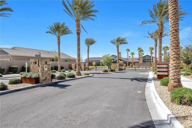 view of street with a gate, a gated entry, and curbs