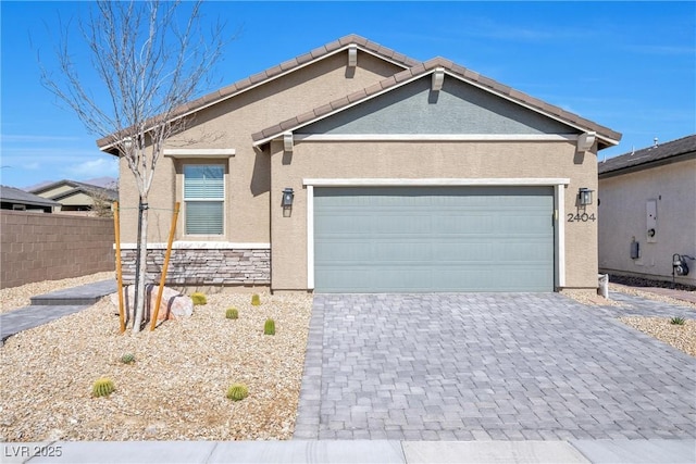 single story home featuring decorative driveway, stucco siding, fence, stone siding, and a tiled roof