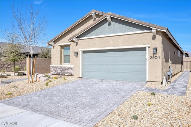 view of front of house featuring decorative driveway, stucco siding, fence, a garage, and stone siding