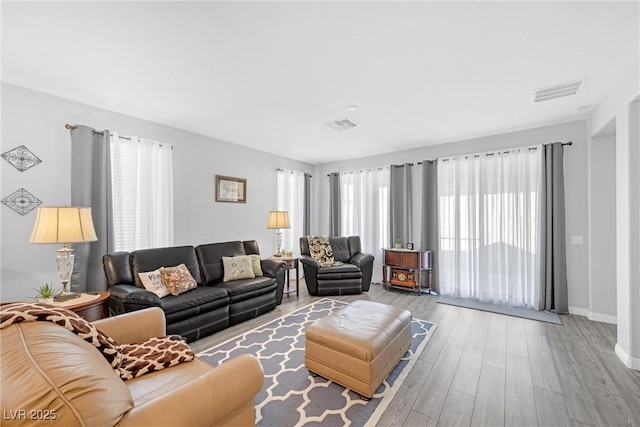 living room with visible vents, baseboards, and wood finished floors