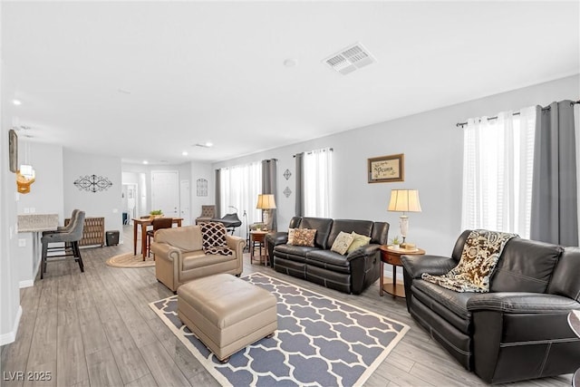 living area with baseboards, visible vents, and light wood finished floors