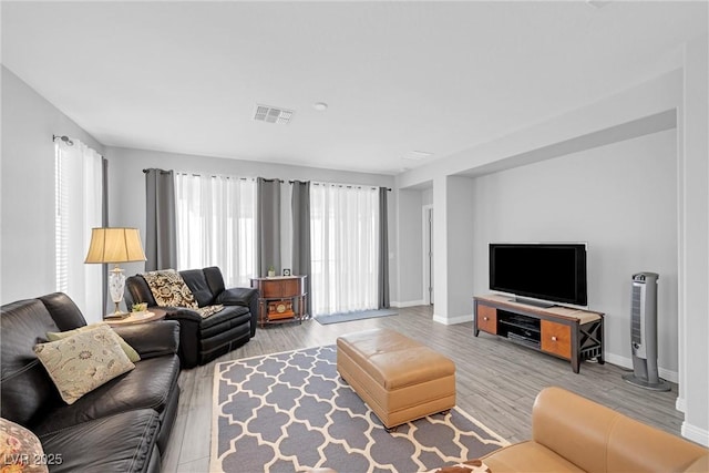 living area with visible vents, baseboards, and wood finished floors