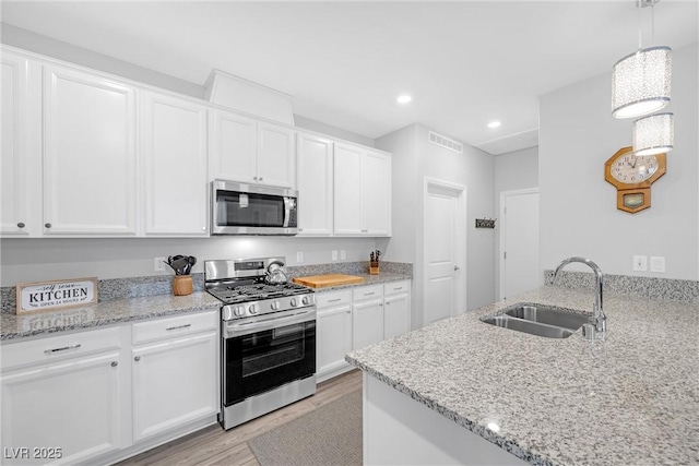 kitchen featuring visible vents, appliances with stainless steel finishes, white cabinets, and a sink