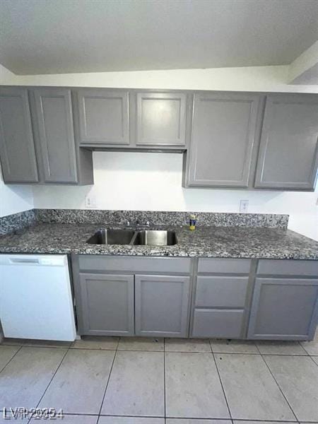 kitchen with a sink, dark stone countertops, gray cabinets, and dishwasher