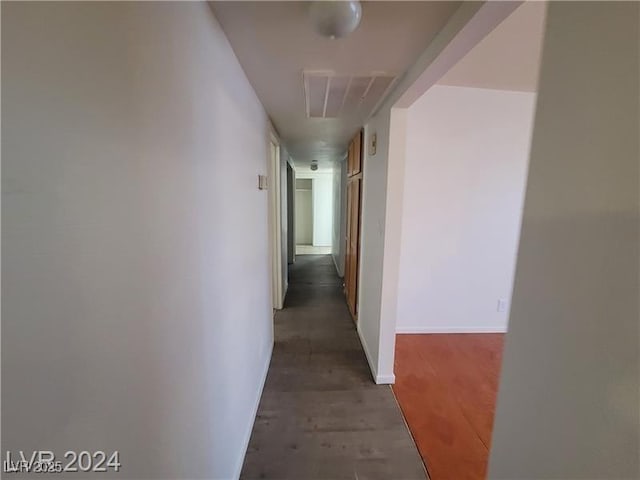 hallway with wood finished floors, visible vents, and baseboards