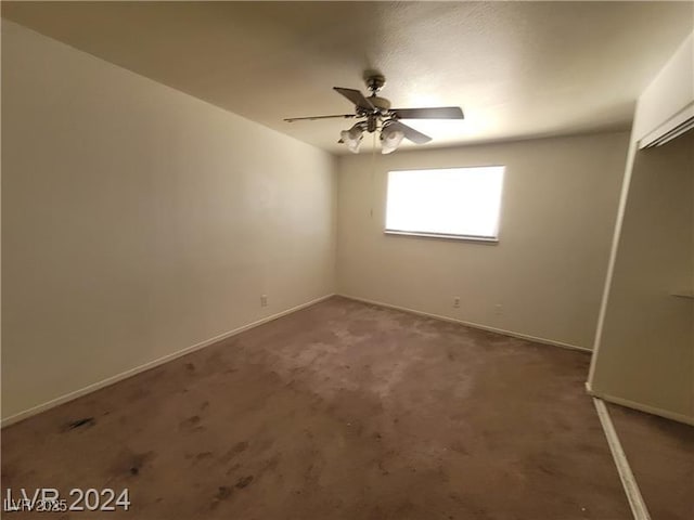 carpeted spare room with a ceiling fan and baseboards