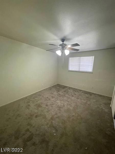 empty room with ceiling fan and dark carpet