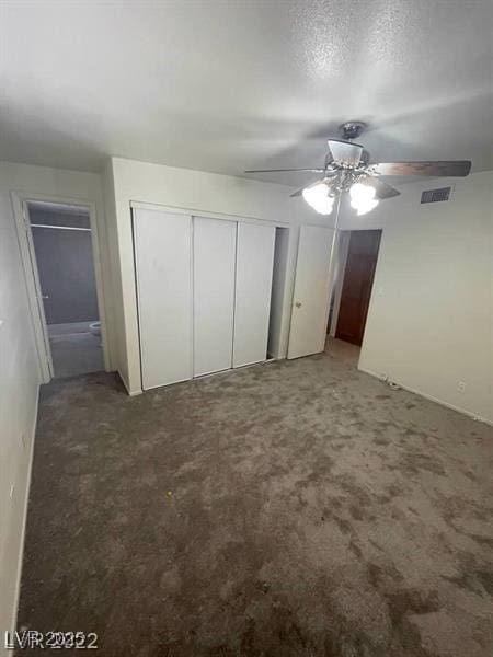 unfurnished bedroom featuring a textured ceiling, light colored carpet, a ceiling fan, visible vents, and a closet