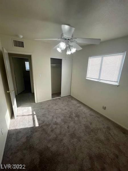 unfurnished bedroom featuring carpet floors, a closet, visible vents, and a ceiling fan