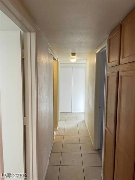 corridor featuring light tile patterned floors and a textured ceiling