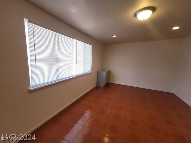 tiled empty room with recessed lighting and baseboards