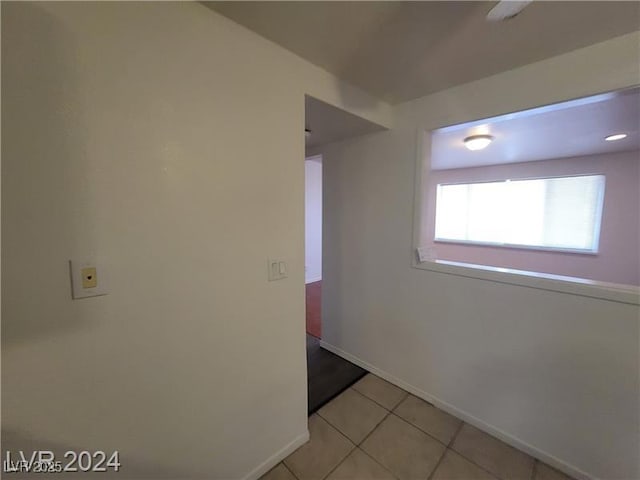 empty room featuring baseboards and light tile patterned floors