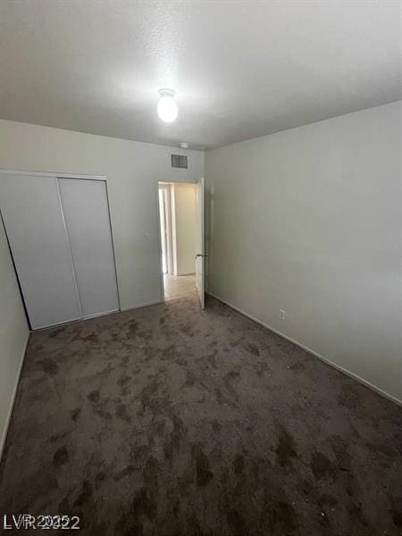 unfurnished bedroom with a closet, visible vents, and carpet flooring