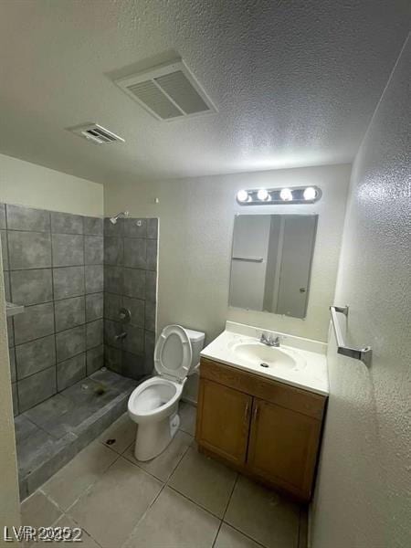 full bathroom with visible vents, tiled shower, toilet, a textured ceiling, and vanity