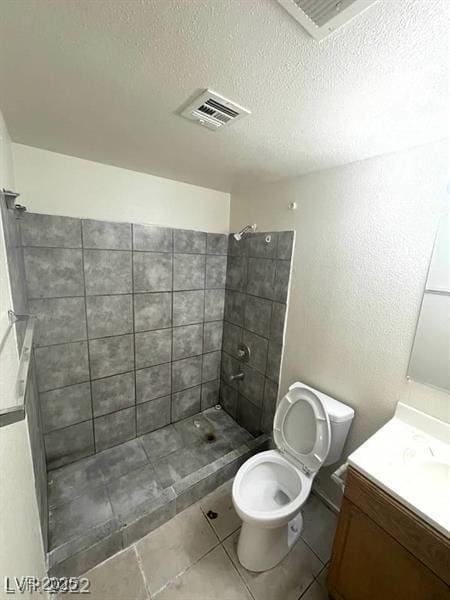 full bath with a textured ceiling, toilet, visible vents, vanity, and tiled shower