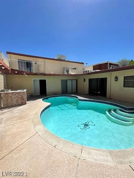 pool with an outdoor kitchen and a patio