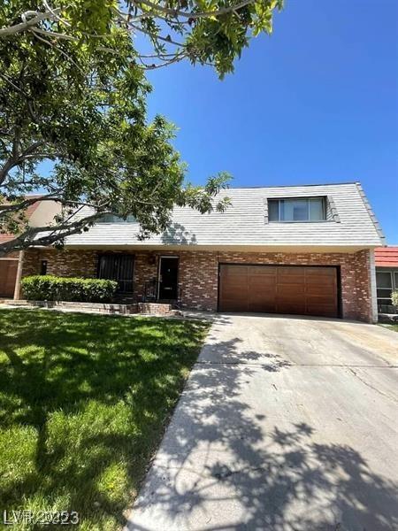 view of front of property with a garage, concrete driveway, a front lawn, and brick siding