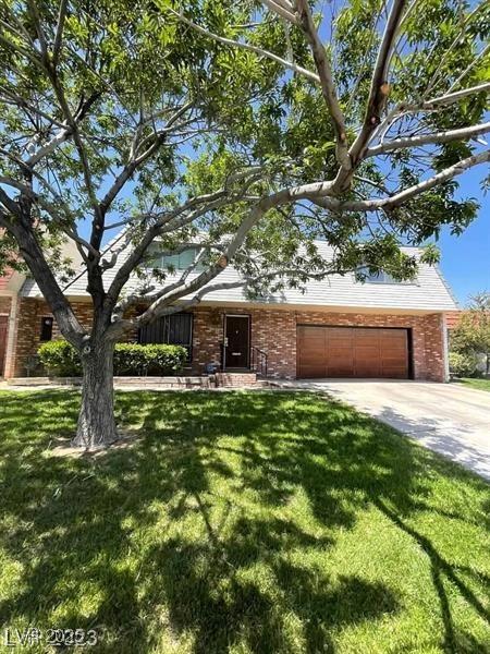 view of front of home with a garage, brick siding, and a front lawn