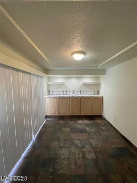 spare room with stone finish flooring, a textured ceiling, and baseboards