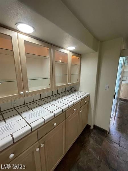 kitchen with glass insert cabinets, tile countertops, and baseboards