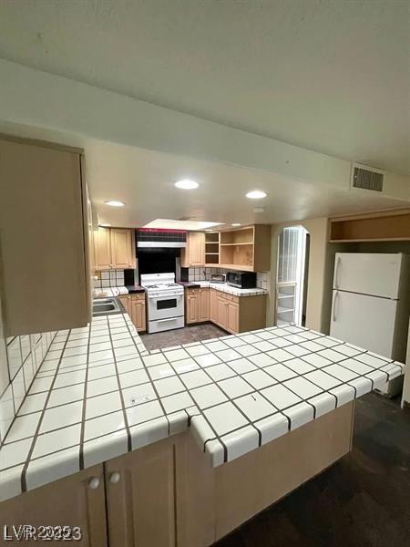 kitchen with tile counters, white appliances, visible vents, and open shelves