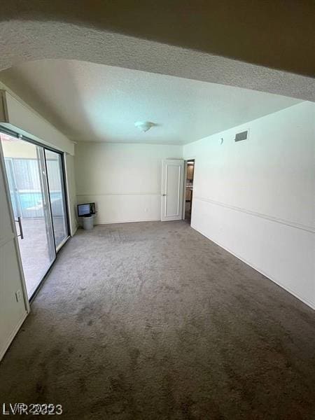 spare room featuring carpet, visible vents, and a textured ceiling