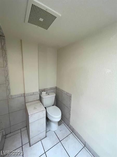 bathroom featuring visible vents, tile walls, toilet, and tile patterned floors