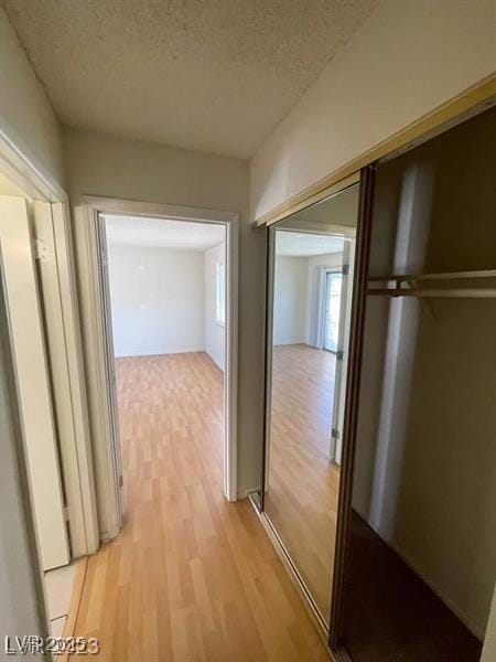 hallway featuring light wood-style flooring and a textured ceiling