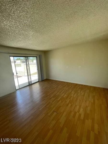 empty room featuring a textured ceiling, baseboards, and wood finished floors